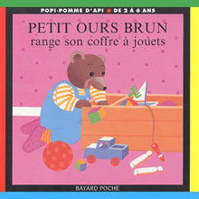 Petit ours brun range son coffre à jouets
